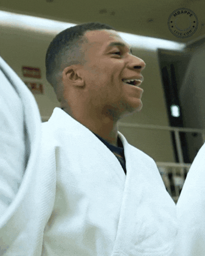 a man wearing a white robe with the word mbappe on the bottom