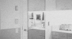 a black and white photo of a person standing in a room with a door open .