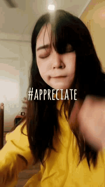 a woman wearing a yellow shirt with #appreciate written on her face