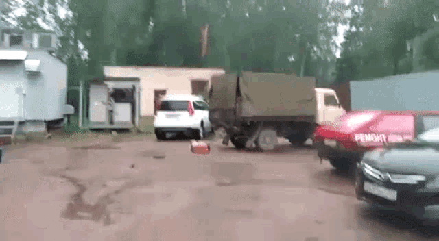 a truck is parked in a parking lot next to a red car that says ' remont ' on the side .