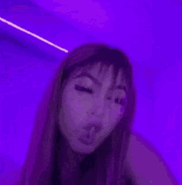 a woman is standing in front of a purple light .