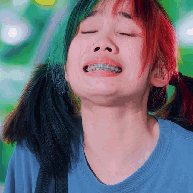 a woman with braces on her teeth looks down with her eyes closed