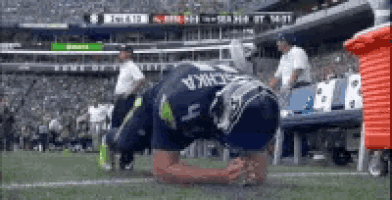 a soccer player is kneeling on the field with his head down .