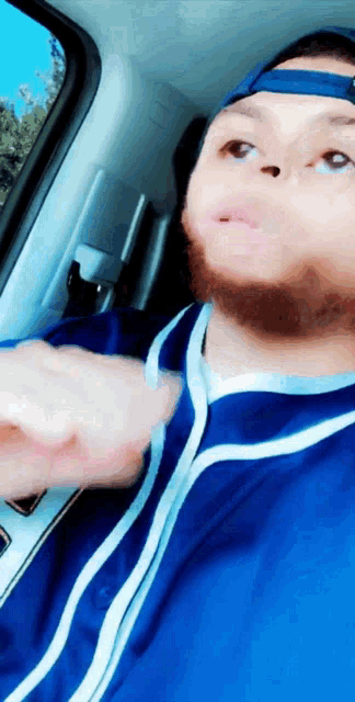 a man with a beard is wearing a blue shirt and a hat