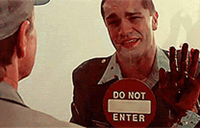 a man with blood on his hands holds a do not enter sign
