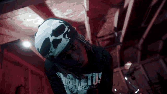 a man wearing a bandana and a skull hat is standing in a dark room with a red light .