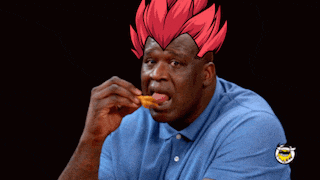 a man in a blue shirt is eating a chicken wing