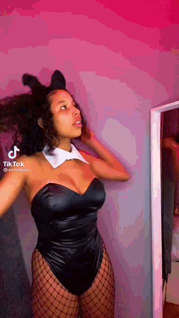 a woman in a bunny costume is standing in front of a mirror in a room .