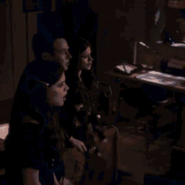 a group of people are standing in a dark room looking up at the sky .