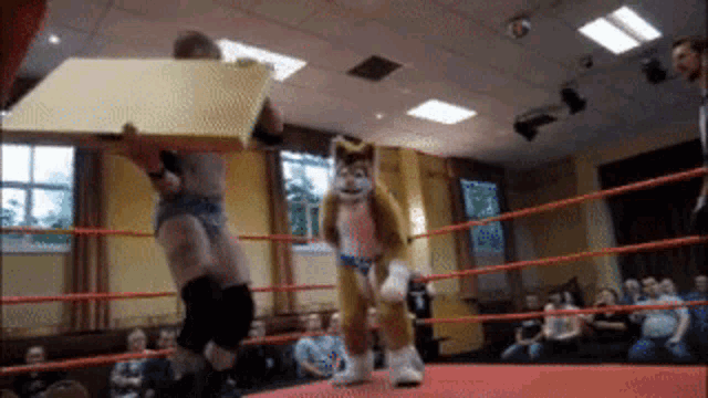 a man in a wrestling ring with a furry mascot behind him