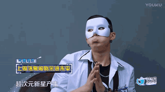a man wearing a white mask is sitting in front of a youku logo
