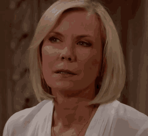 a close up of a woman 's face wearing a white shirt and necklace .