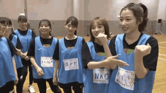 a group of girls wearing blue vests with nao written on the front