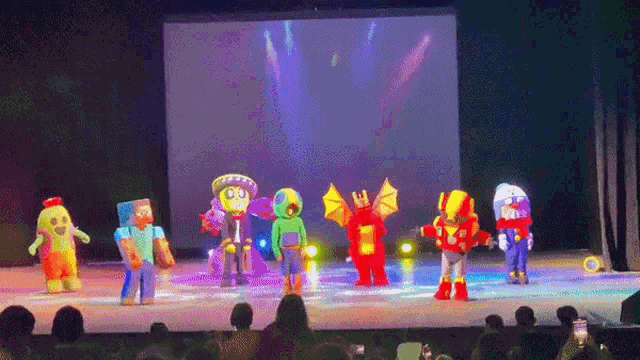 a group of mascots are on a stage in front of a large screen