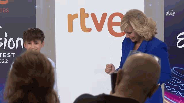 a woman in a blue suit stands in front of a rtve sign