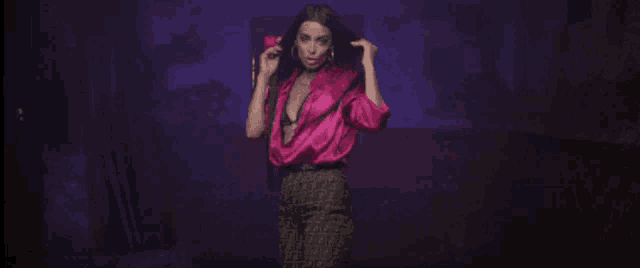 a woman in a pink satin shirt and pants is dancing on a stage .