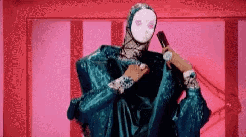 a woman in a blue dress and mask is holding a microphone in her hand .