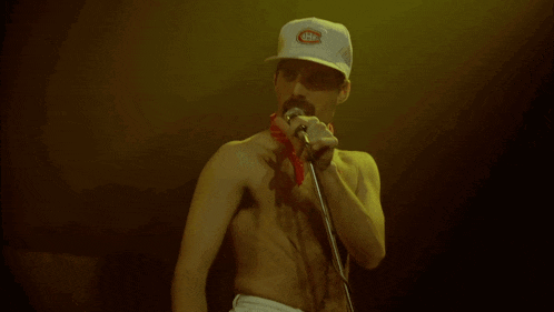 a man singing into a microphone wearing a hat