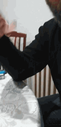 a man in a black sweater is laying on a white blanket