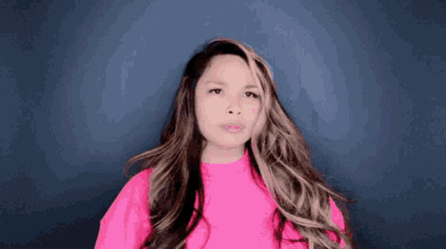 a woman with long hair wearing a pink shirt