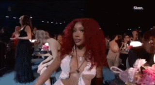 a woman with red hair is standing in front of a crowd at a concert .