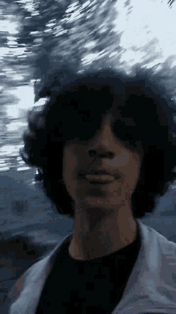 a man with curly hair wearing sunglasses and a black shirt
