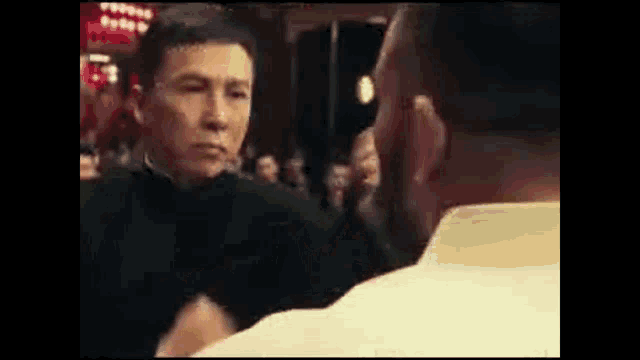 two men are standing next to each other and looking at each other in front of a crowd .