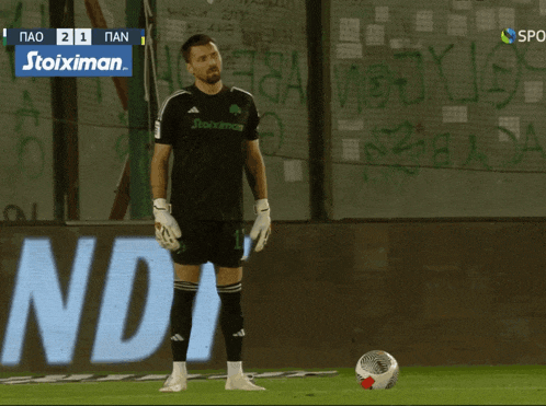 a soccer player stands in front of a sign that says " stoiximan "