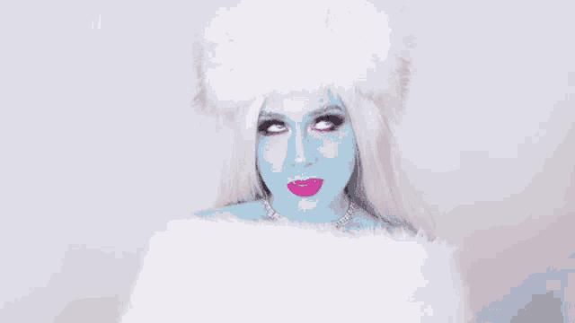 a woman with blue makeup and white hair is wearing a white fur coat and a white hat .
