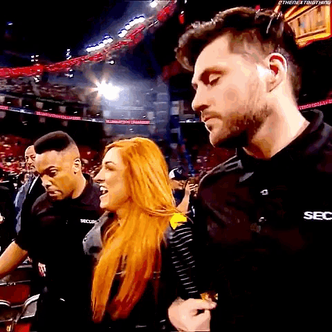 a man wearing a black shirt that says sec is standing next to a woman with red hair