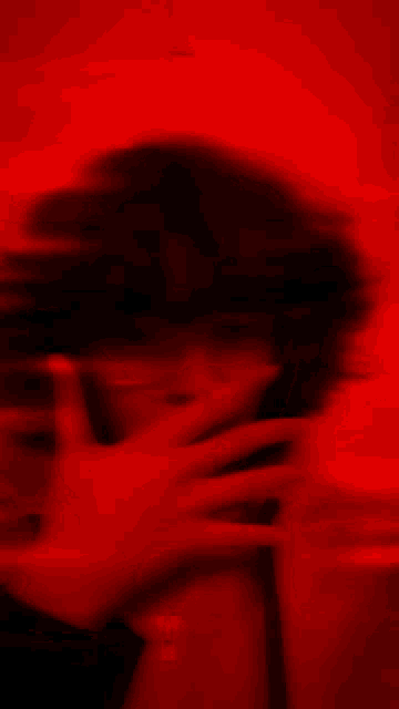 a blurry picture of a person taking a selfie in front of a red wall .