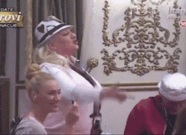 a woman in a hat is standing next to another woman in a room with a sign that says ' lovi ' on it