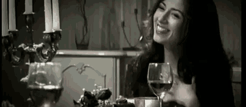 a woman is sitting at a table with a glass of wine in her hand .