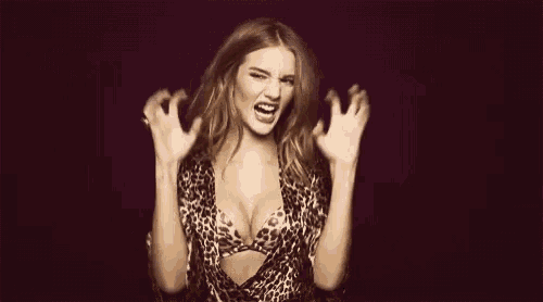 a woman in a leopard print bra is making a funny face with her hands outstretched .