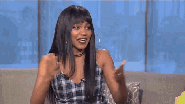 a woman in a plaid top is sitting on a couch with her hands outstretched