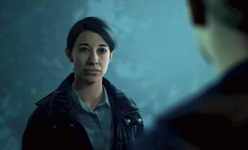 a woman in a black jacket looks at a man in a blue jacket