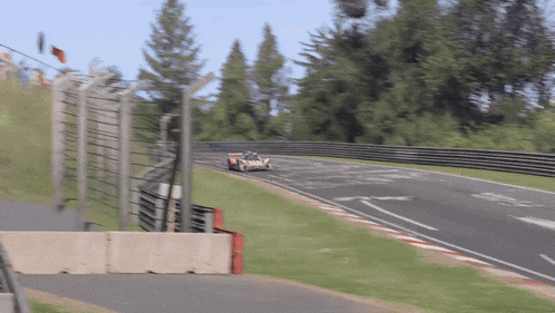 a race car is going down a track with a fence in the background