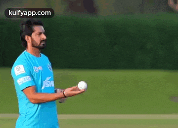 a man in a blue shirt is throwing a cricket ball .