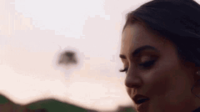 a close up of a woman 's face with mountains in the background .