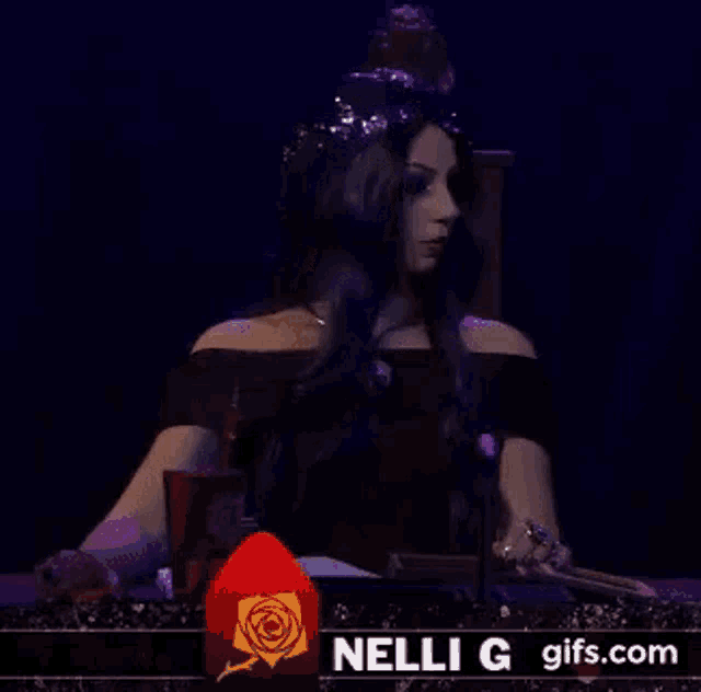 a woman in a black dress is sitting at a table in front of a microphone and a red rose .