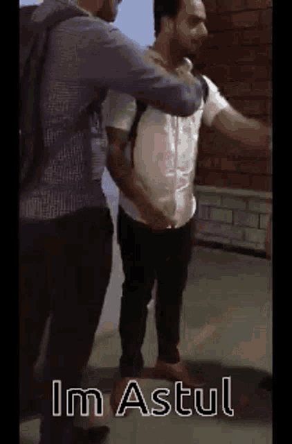 two men are standing next to each other and one of them is holding the other man 's arm .