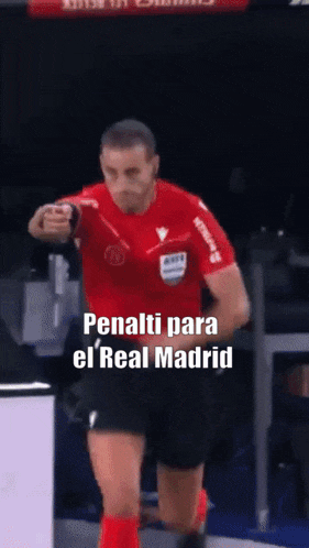 a referee in a red shirt and black shorts is giving a thumbs up
