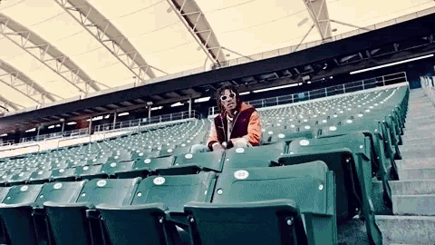 a man sits in an empty stadium with a row of green seats with the numbers 22 and 23 on them