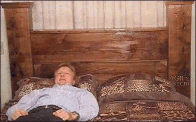 a man is laying on a bed with a wooden headboard and a leopard print blanket
