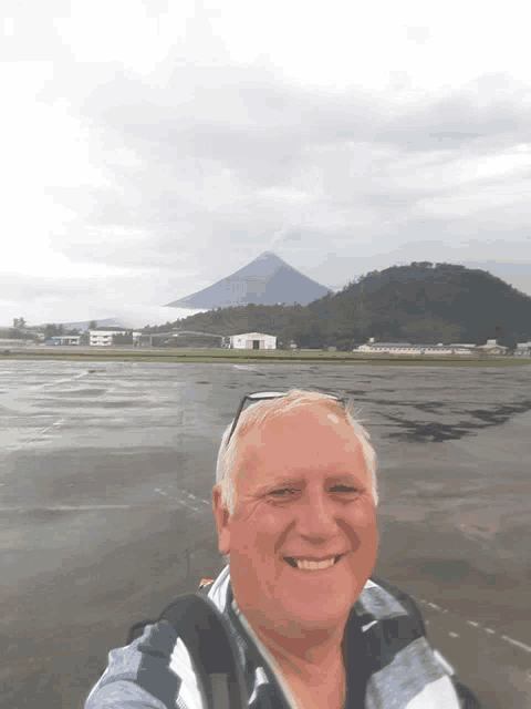 a man smiles in front of a mountain in the background
