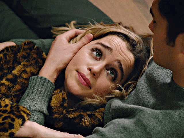 a woman in a leopard print jacket is laying on a man 's chest