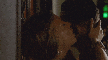 a man and a woman kissing with a green light behind them