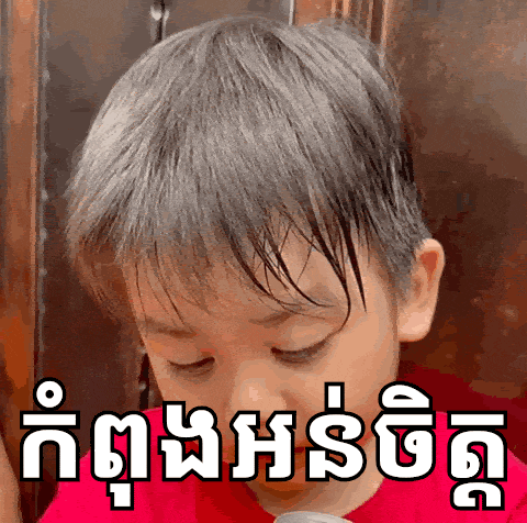 a young boy with a red shirt on has a foreign language written on his face