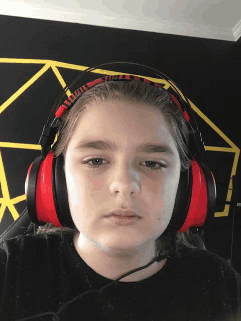 a young boy wearing a pair of red and black headphones looks at the camera