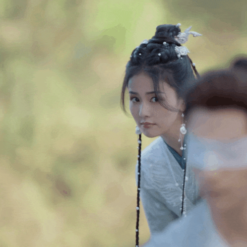 a woman with braids and pearls in her hair looks to the side